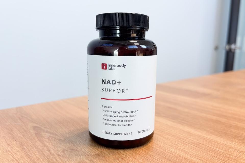 A glass bottle of Innerbody Labs NAD+ Support sitting on a wooden countertop.