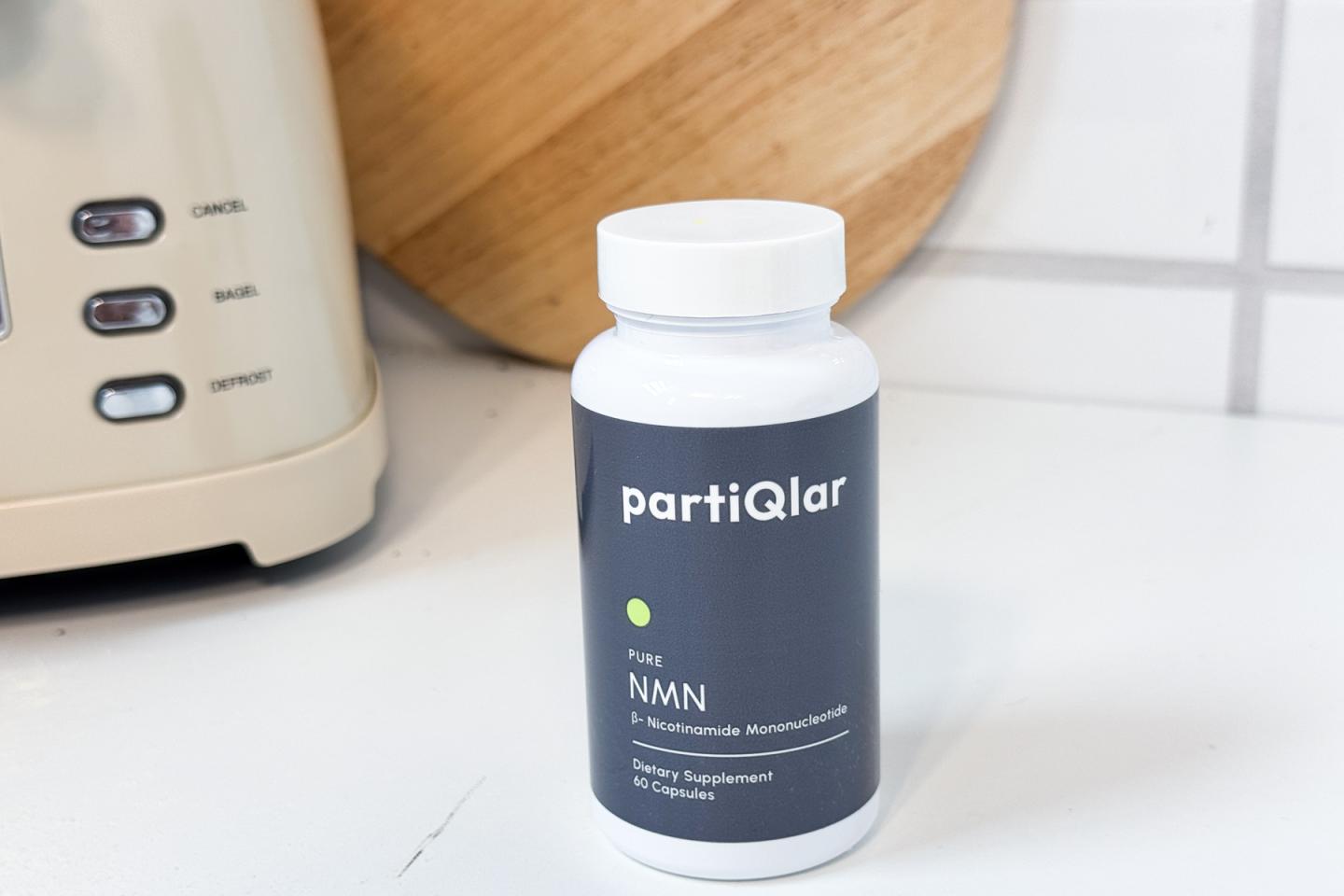 A bottle of partiQlar NMN sitting on a white countertop.